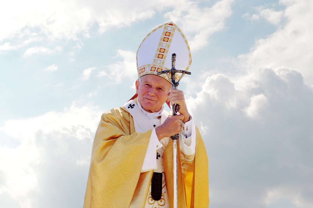 Obraz przedstawia opierającego się na feruli (pastorale z wizerunkiem Chrystusa ukrzyżowanego) papieża Jana Pawła II ubranego w strój liturgiczny: ornat koloru złotego, paliusz oraz białą mitrę ze zdobieniami.
